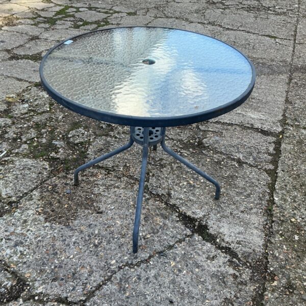 Round glass topped garden patio table with dark rim and metal base