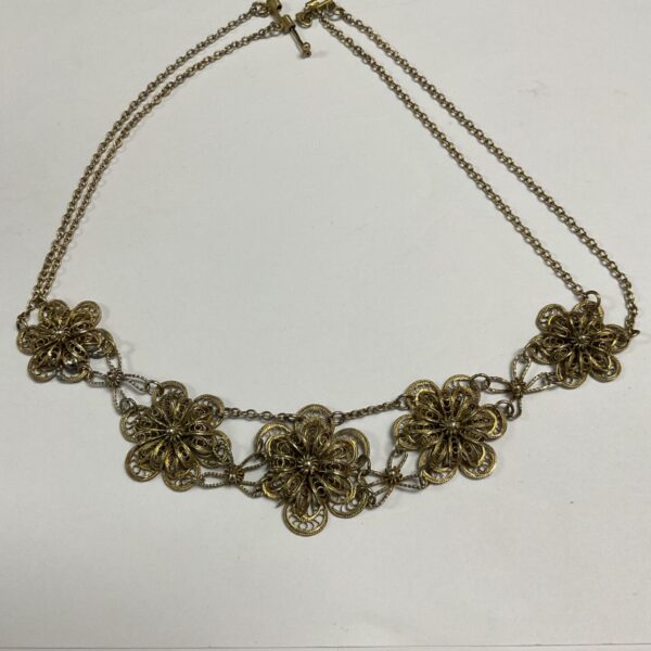 Gold toned metal filigree flower necklace with openwork floral motifs on chain