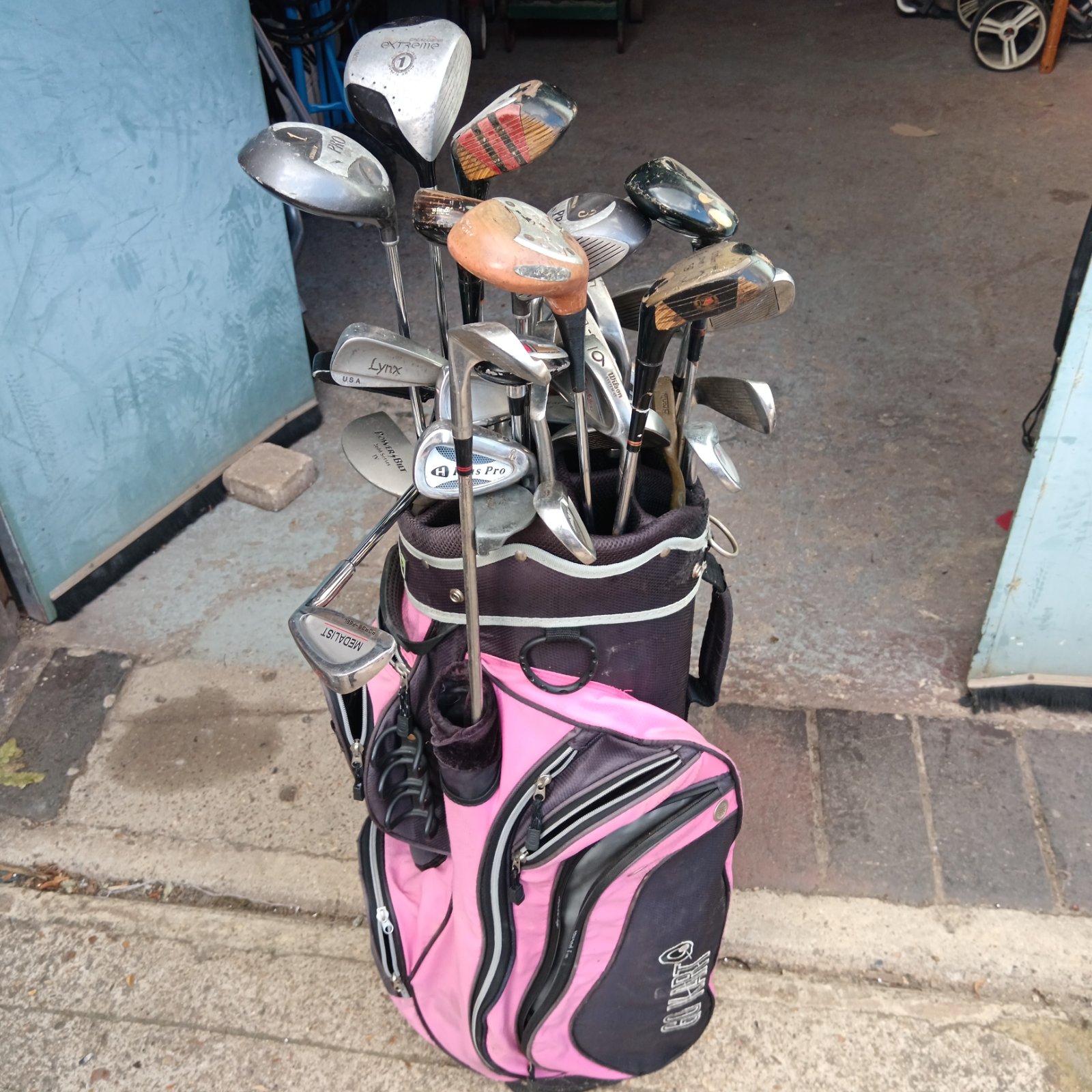 Vintage golf club lot in pink bag, showing various brands.