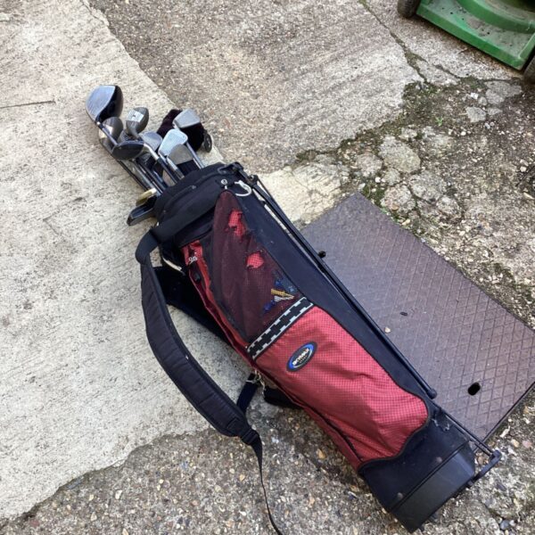 Red and black golf bag with a selection of golf clubs.