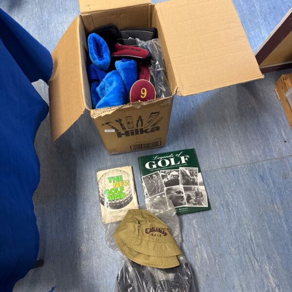 Box of golf head covers with Callaway hat and golf books