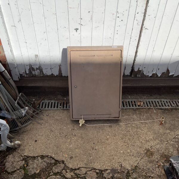 Grey metal meter housing box with key for outdoor utility protection.