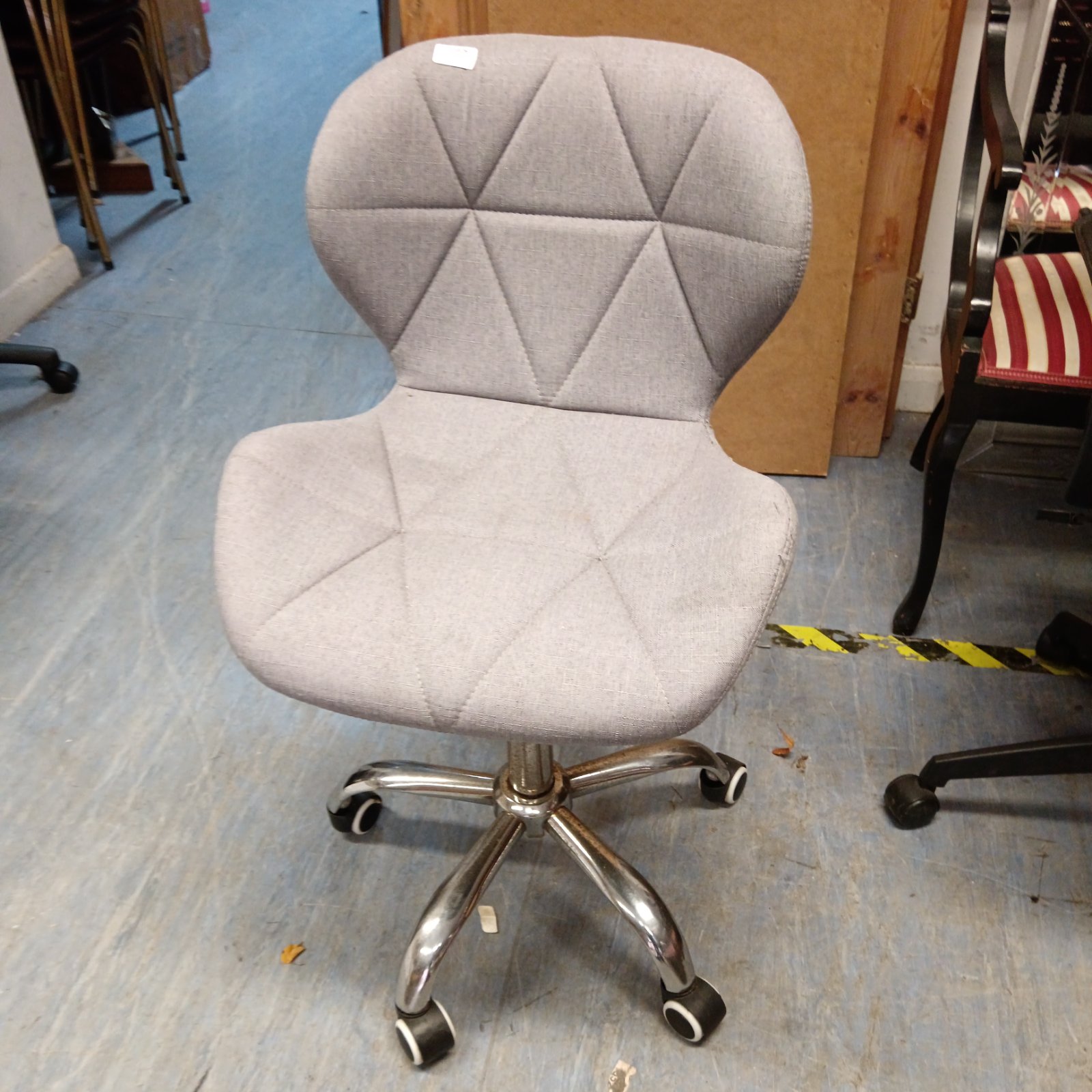 Modern grey office chair with chrome base and swivel function.