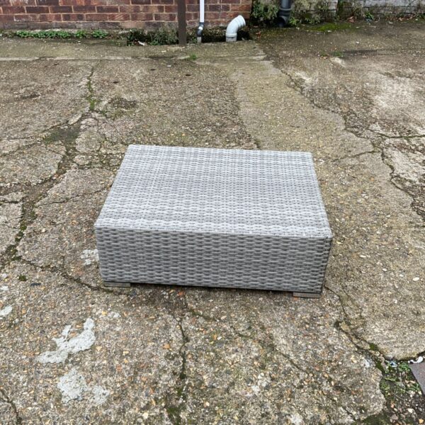 Grey woven low level garden table with rectangular top on paved patio