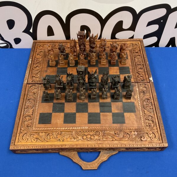 Hand carved Indonesian wooden chess set with sculpted pieces on carved folding board