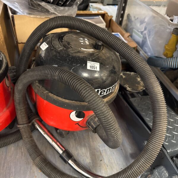Red Numatic Henry Hoover vacuum cleaner with hose attached.