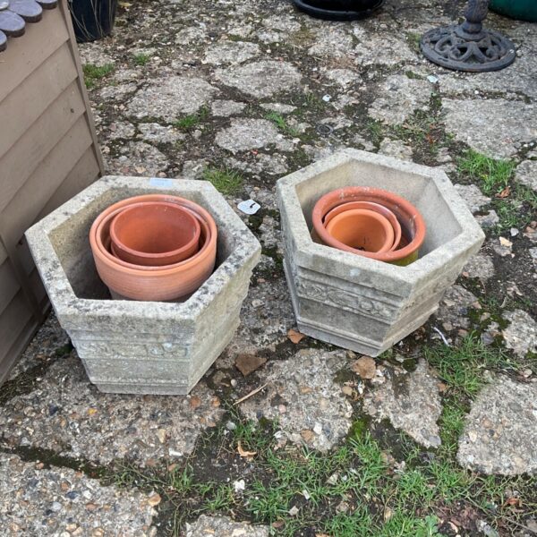 Pair of weathered hexagonal stone planters in a garden setting.