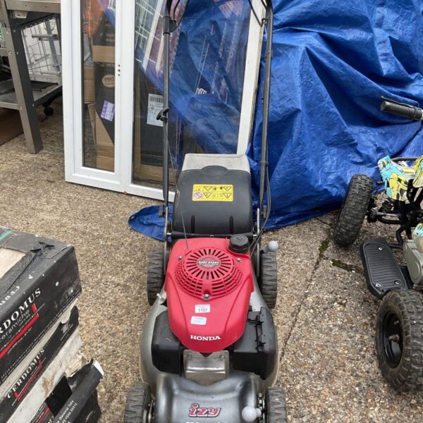 Side view of a used Honda Izy petrol lawnmower in a garden setting.