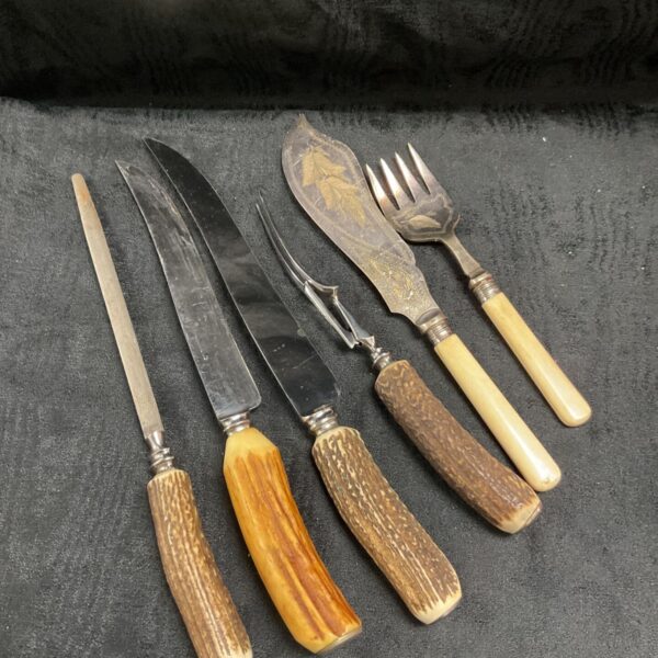 Horn and bone handled carving knives and forks set laid out on dark fabric