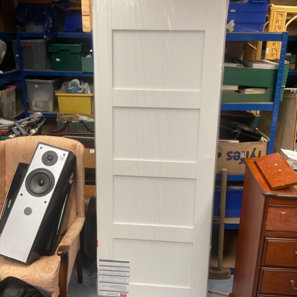 White Howdens Promed timber door with panelled design, shown upright in a storeroom