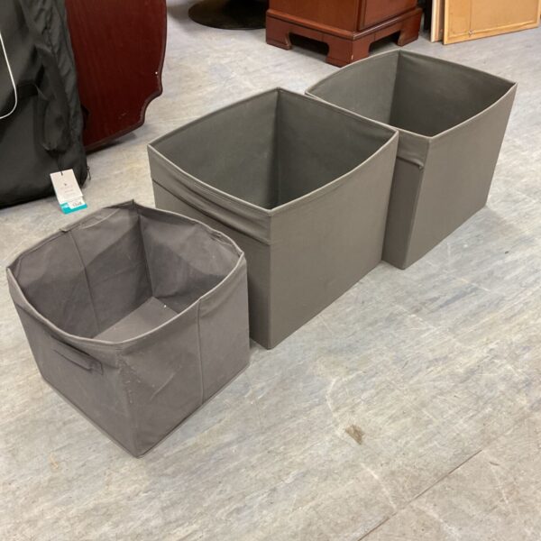 Three grey fabric IKEA folding storage boxes, two large and one small