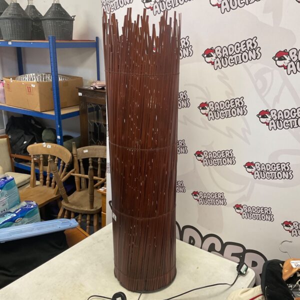 Tall cylindrical IKEA rattan floor lamp with brown woven slats and round base