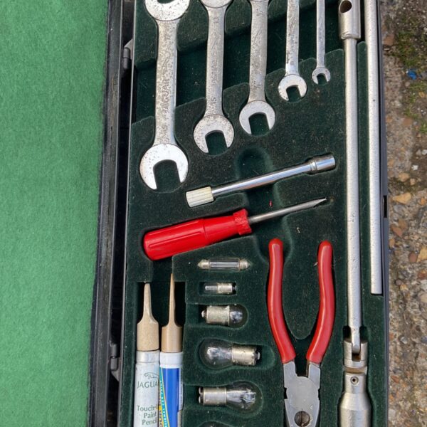 Open Jaguar tool kit showing vintage spanners and tools.