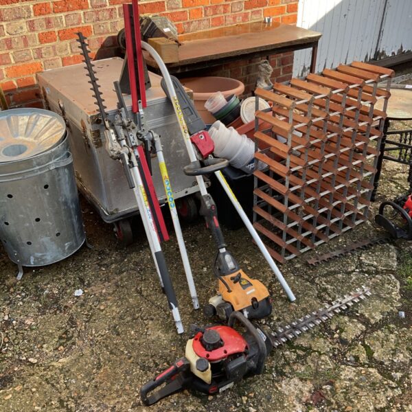JCB petrol strimmer and red petrol hedge cutter with garden attachments on paving