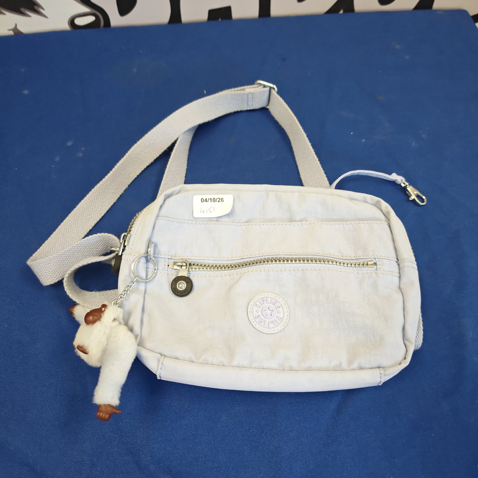 Beige Kipling shoulder bag with monkey keychain detail.