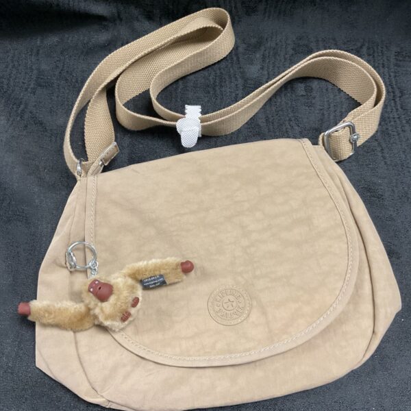 Light tan Kipling shoulder bag with Shiloh ape charm and adjustable strap