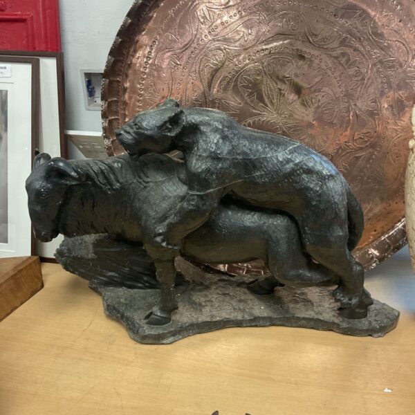 Dramatic springstone sculpture of a lion hunting a wildebeest by Robin Kutinyu.