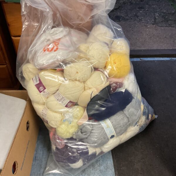 Large clear bag filled with mixed cream, yellow and navy balls of wool