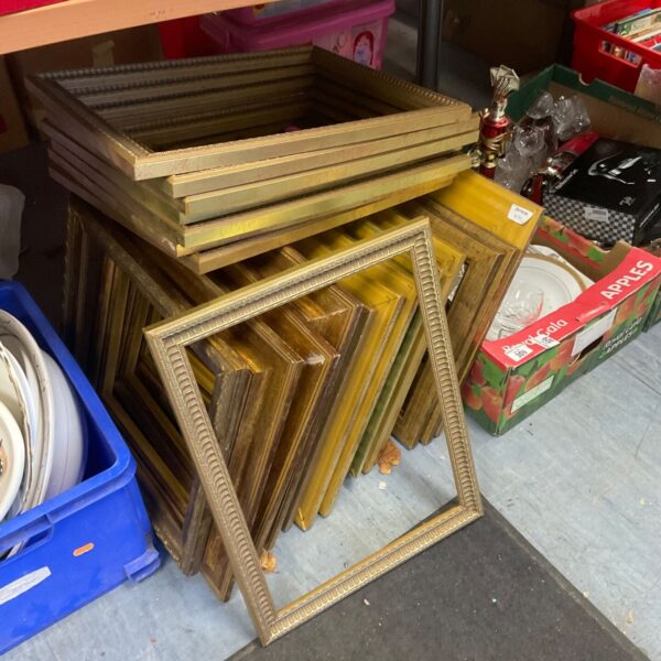 Large quantity of gilt picture frames stacked on floor, various sizes