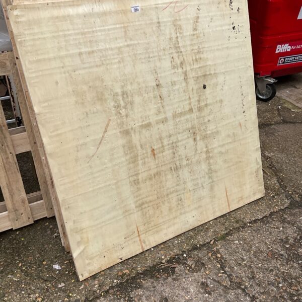 Stack of large plywood sheets leaning against wooden pallet outdoors