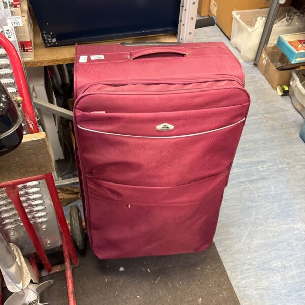 Large red Supreme soft-sided suitcase with top handle and wheels