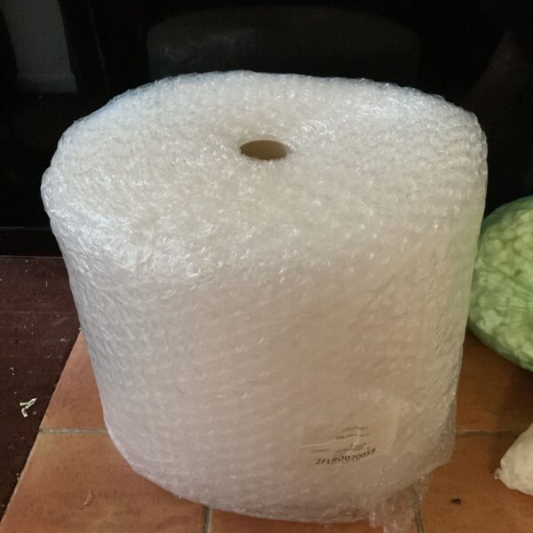 Large roll of clear bubble wrap standing upright on terracotta tiles