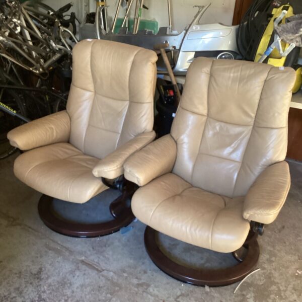 Two tan leather swivel recliner chairs in a room.