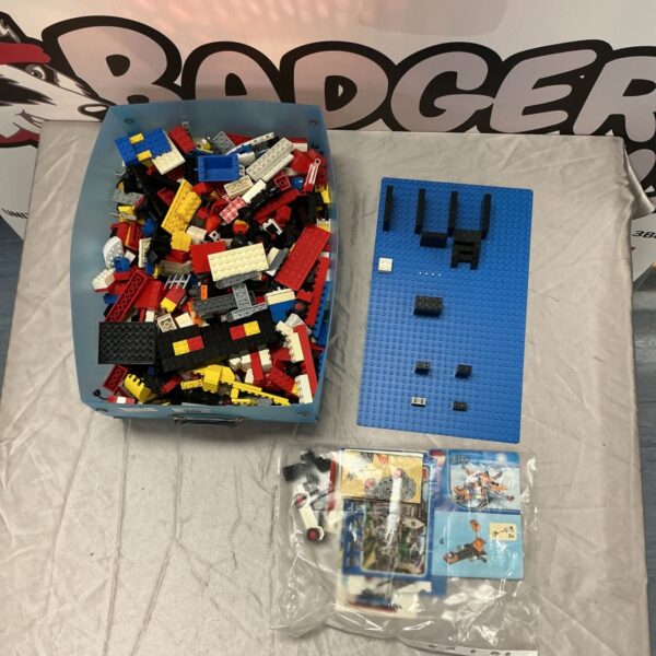 Mixed LEGO bricks in blue tray with baseplate and City instruction booklets