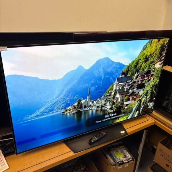 LG OLED55B6V OLED flatscreen television on wooden stand with remote control