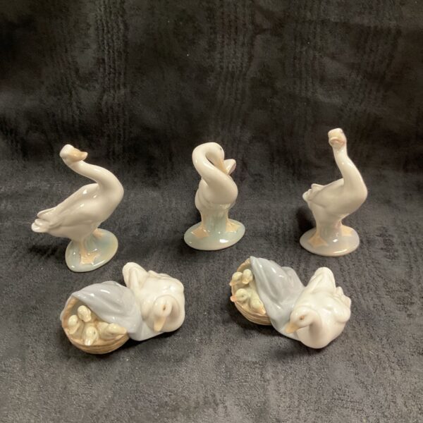 Five Lladro porcelain geese figures, three standing and two seated with goslings