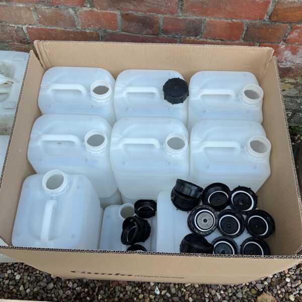 Eighteen new white plastic water containers and black screw lids in cardboard box