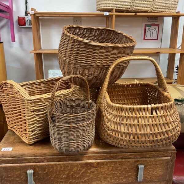 Assorted wicker baskets in natural and golden tones on a wooden chest