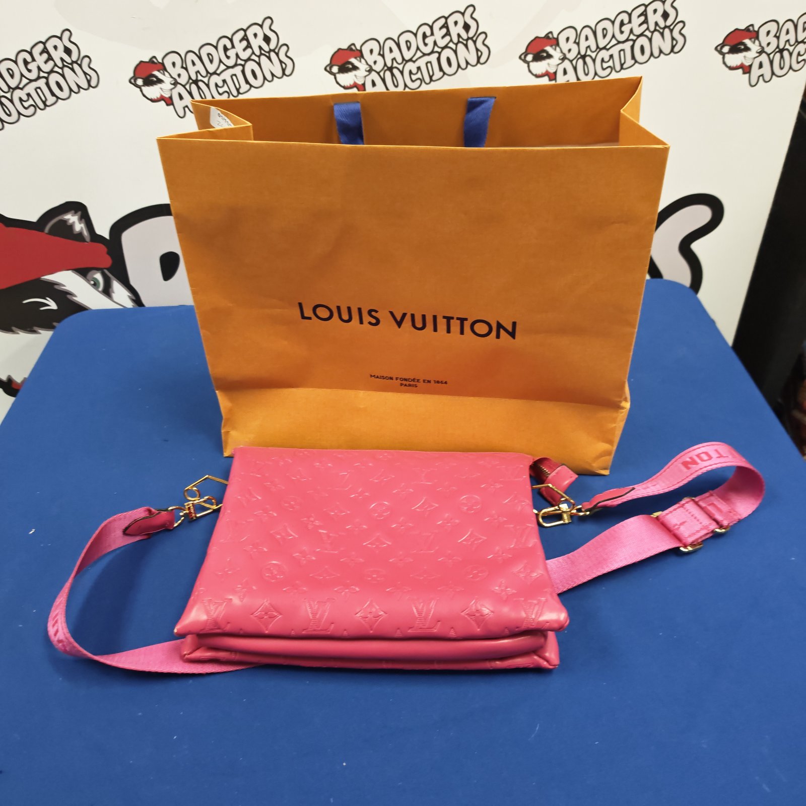 Pink Louis Vuitton style shoulder bag with embossed monogram pattern and carrier bag