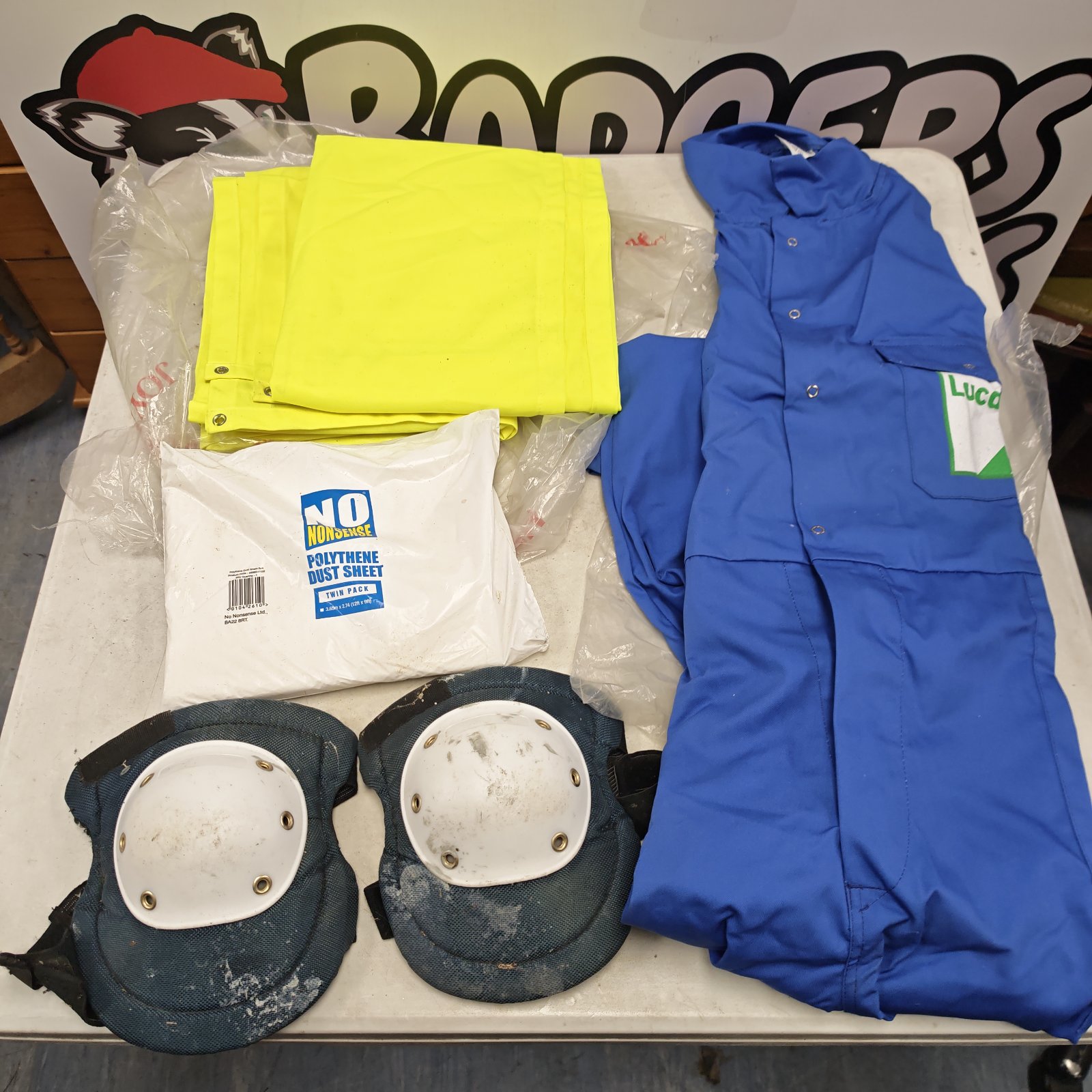 Lucas workshop overalls with knee pads and dust sheets laid out on table