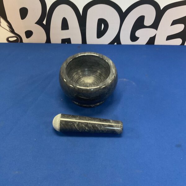 Grey and black marble mortar and pestle set for grinding spices.