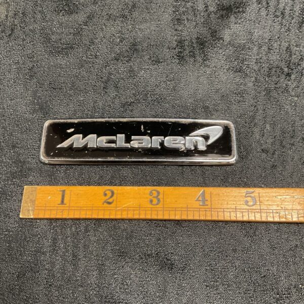 Vintage McLaren car badge, chrome emblem, automotive collectible.