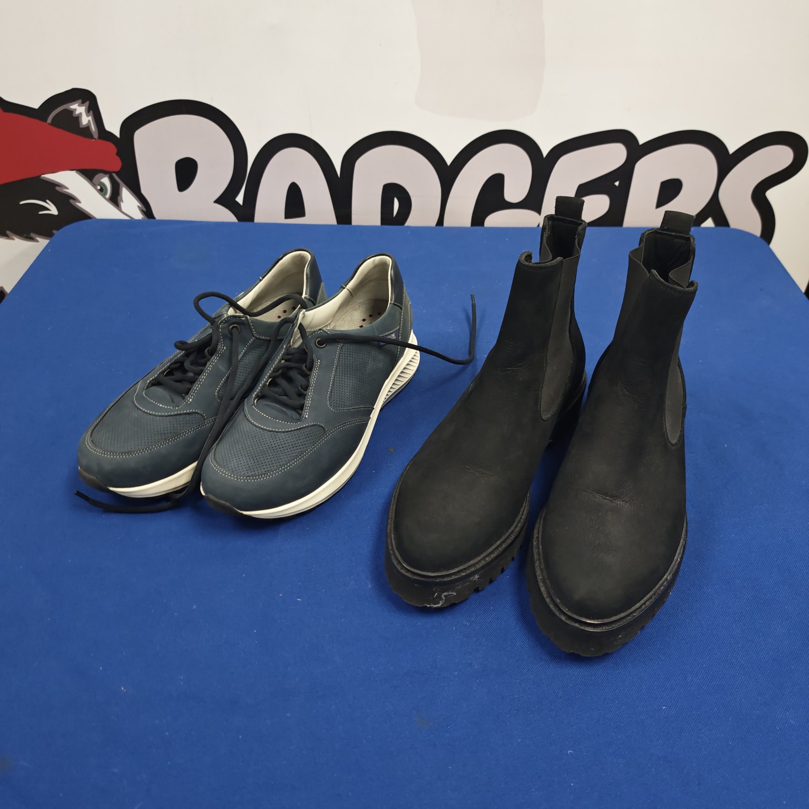 Dark blue Mephisto trainers beside black leather Air&Grace ladies boots on blue surface
