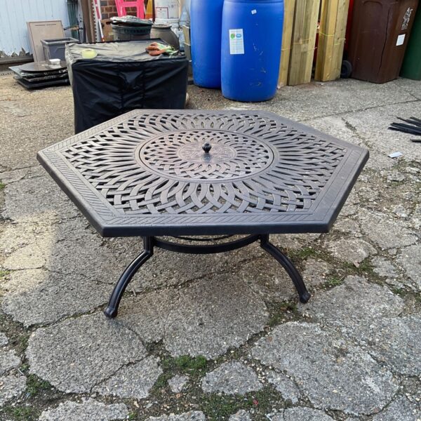 Large metal fire pit table in a garden setting.