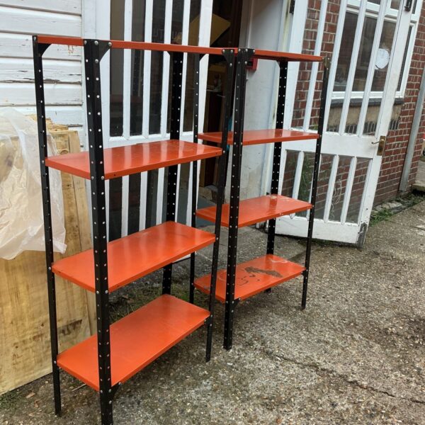 Two sets of orange and black metal garage shelving standing outdoors