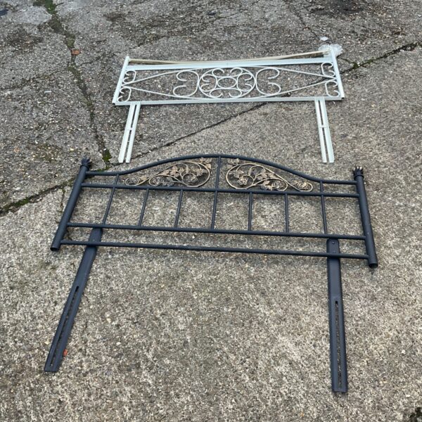 Two metal headboards, one white with scrolls and one dark grey with gold floral detail