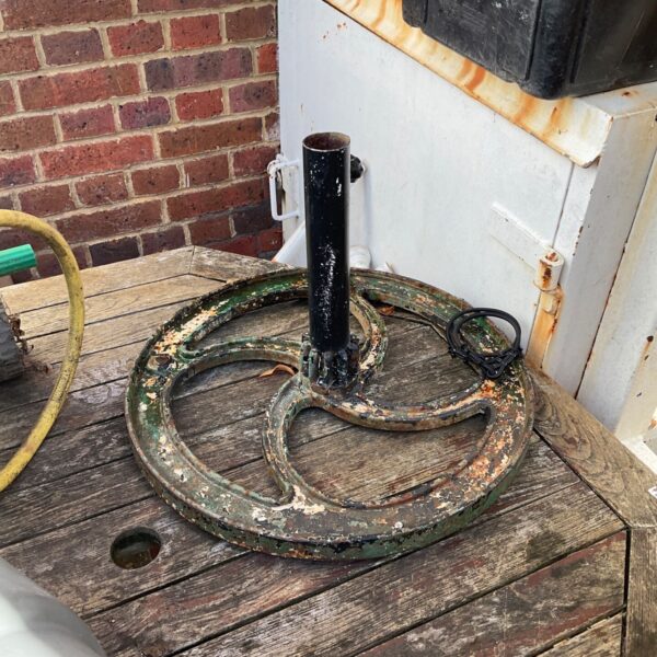Vintage metal parasol base with rust and patina.