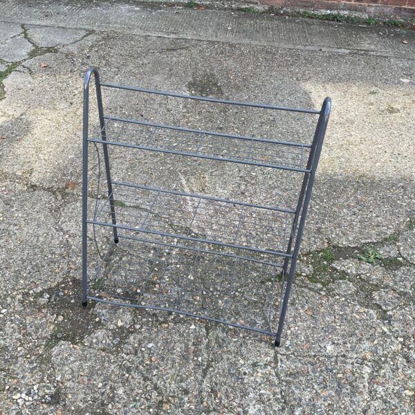 Tiered metal plant stand for displaying potted plants in a garden.