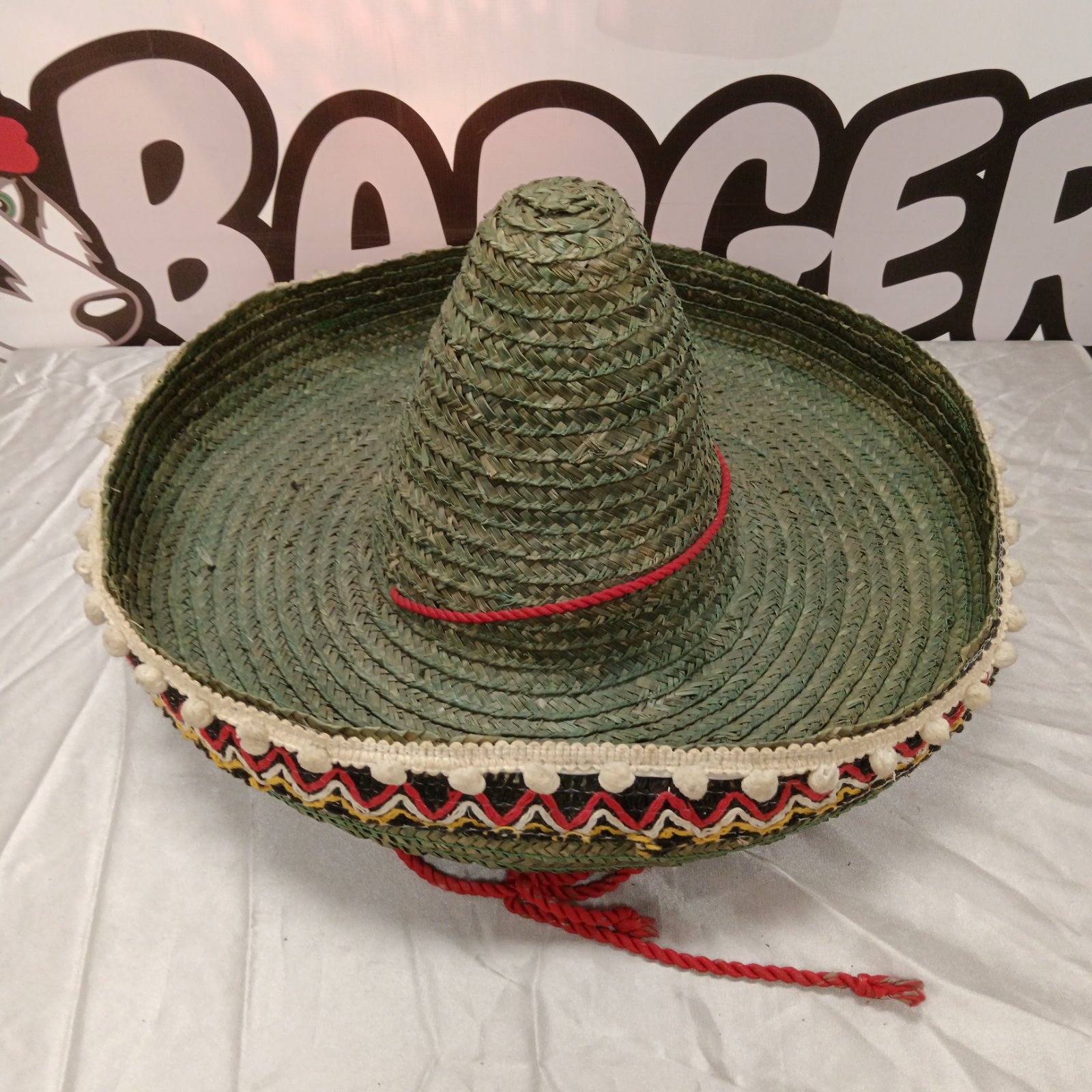 Green woven straw Mexican sombrero hat with cream pom-pom trim and embroidered brim
