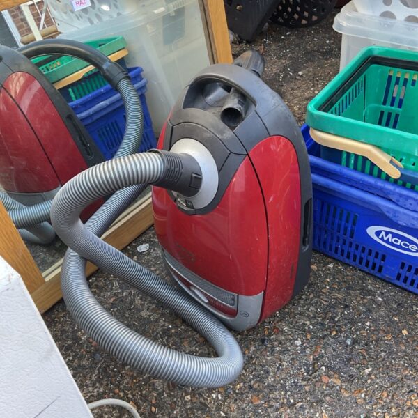 Red Miele Cat and Dog Turbo 5000 vacuum cleaner with grey hose on pavement