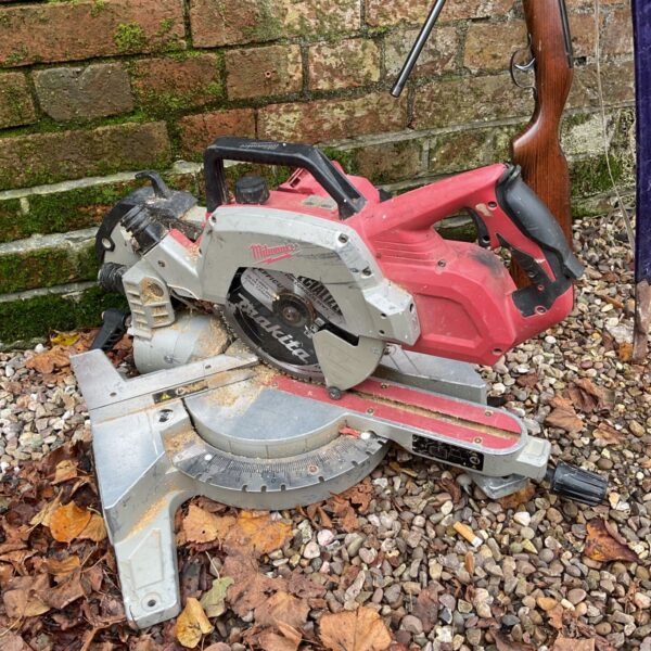 Milwaukee chopsaw with Makita blade on gravel beside autumn leaves