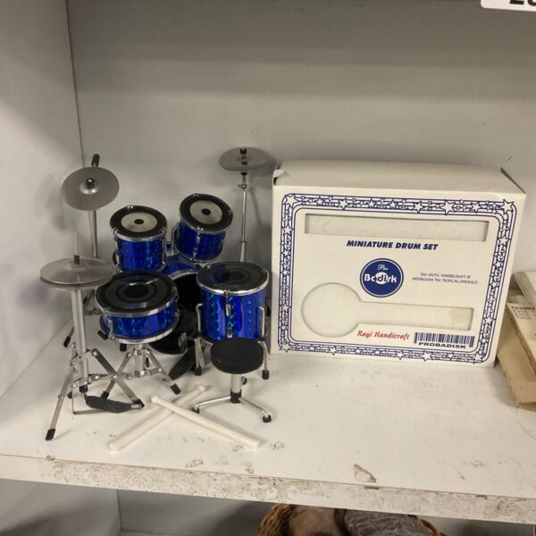 Blue sparkle miniature drum set with cymbals, stool and sticks beside its box