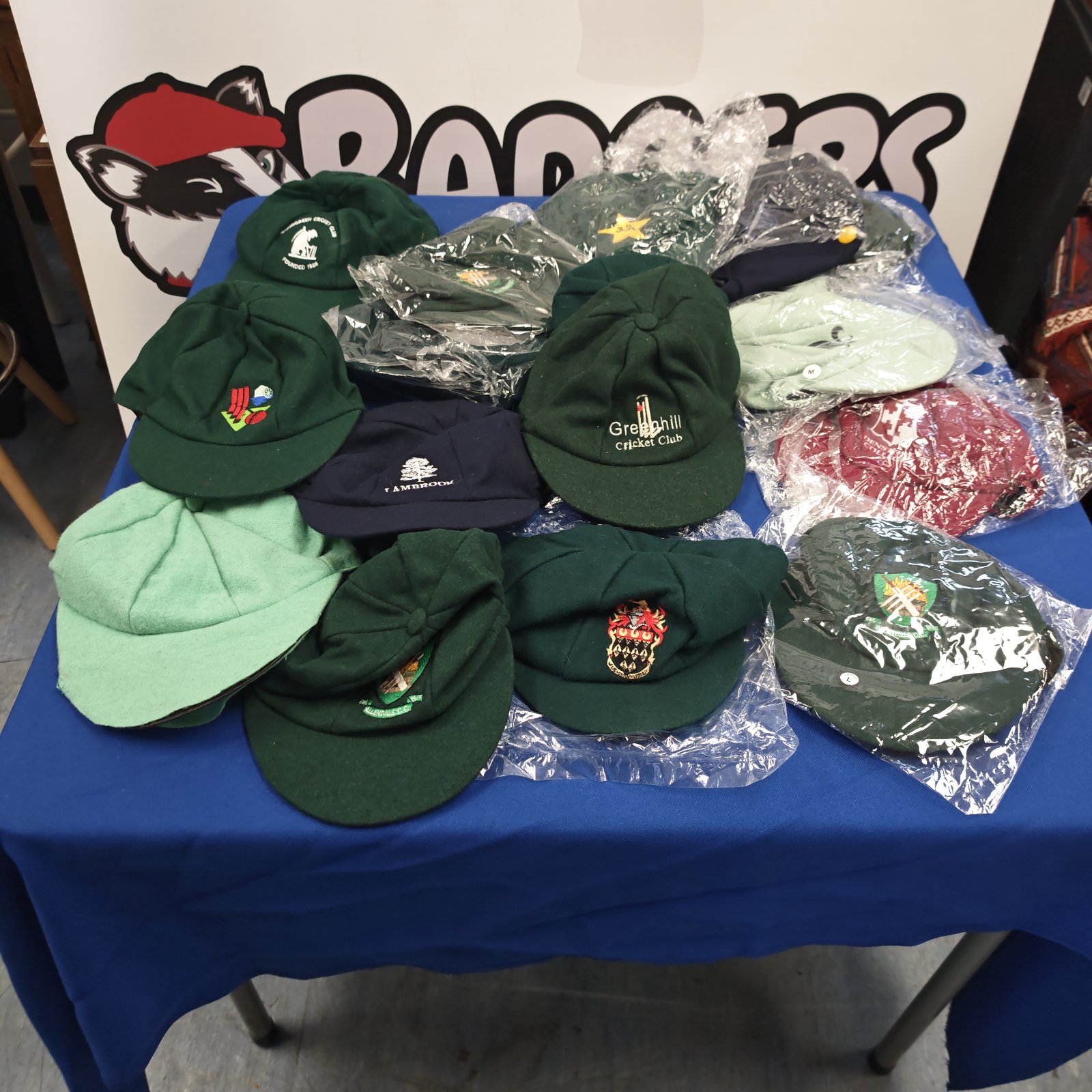 Mixed bag of green, navy, mint and maroon cricket club caps with embroidered badges