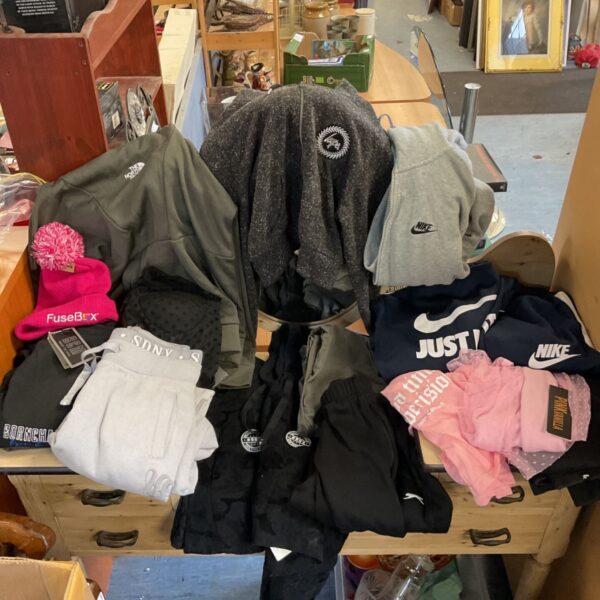 Mixed clothing lot with Nike and The North Face jackets and sweatshirts on a wooden chest