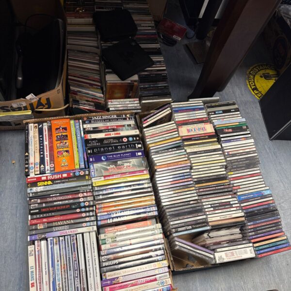 Mixed lot of music CDs and DVDs arranged in cardboard boxes on a floor