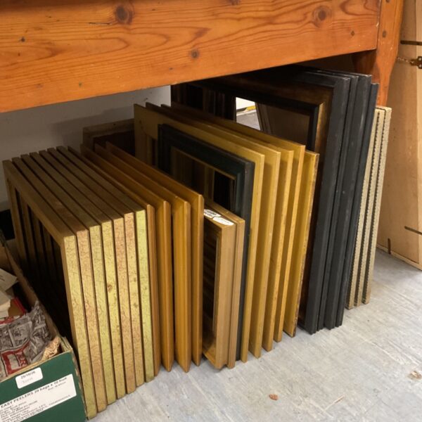Large lot of mixed size gold and black picture frames stacked on floor